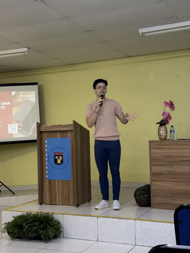 Erikson Oliveira palestrando com microfone para estudantes de Psicologia